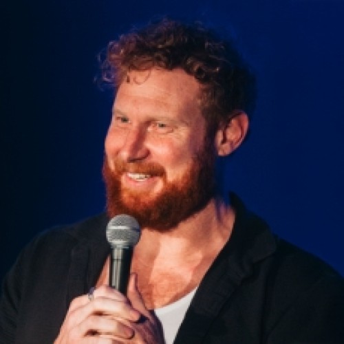 Comedian Ben Knight Smiling as he talks into a microphone on stage, text reads Ben Knight - The Parent/Teacher Interview