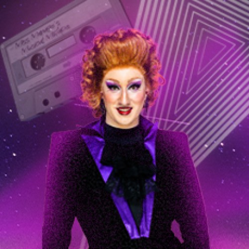 DRAG Queen Miss Manages in a fabulous red wig and purple makeup wears a velvety purple suit. Behind her is a purple, retro background with illustrated triangle shapes and cassette tapes.