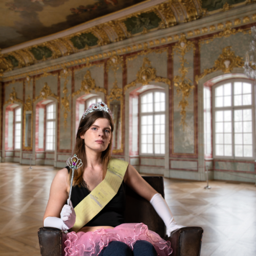 Sophie Stone sits dressed like a princess agaisnt a castle backdrop. 