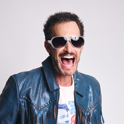 A photo of Josh Wolf wearing stylish sunglasses, a blue leather jacket, and graphic t-shirt